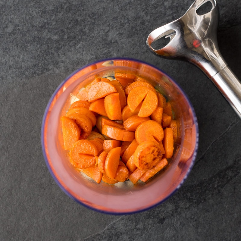 Behälter mit Karotten und Cashew-Kernen, daneben ein Pürierstab um einen Karotten-Aufstrich zu machen