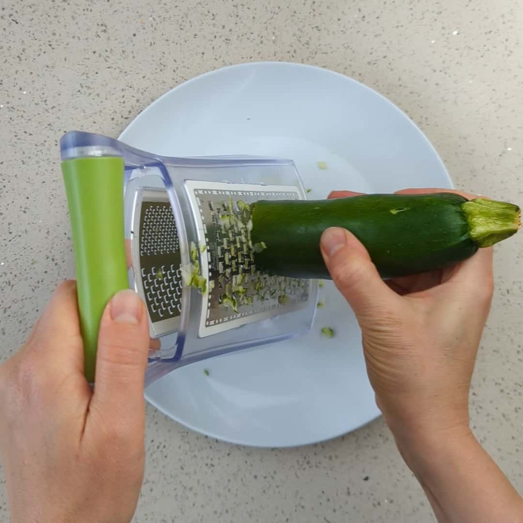 Zucchini die mit einer Reibe fein gerieben wird