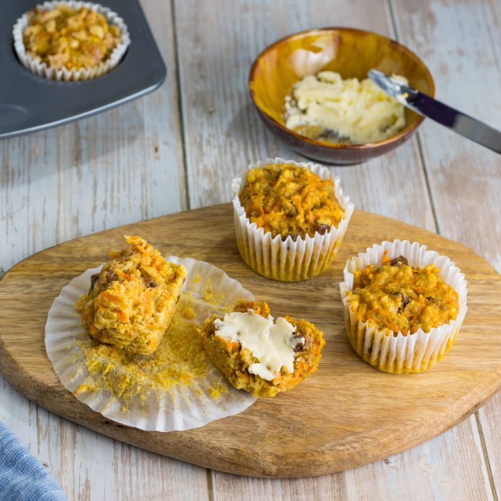 saftige Karottenmuffins ohne Zucker, auf einem Holzbrett, ein Muffin ist mit Butter beschmiert