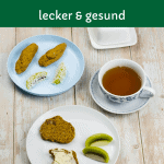 Veganer Scone aufgeschnitten auf einem Teller und mit Butter bestrichen, daneben eine Tasse Tee und ein Babyteller mit länglichen Scones und Kiwi