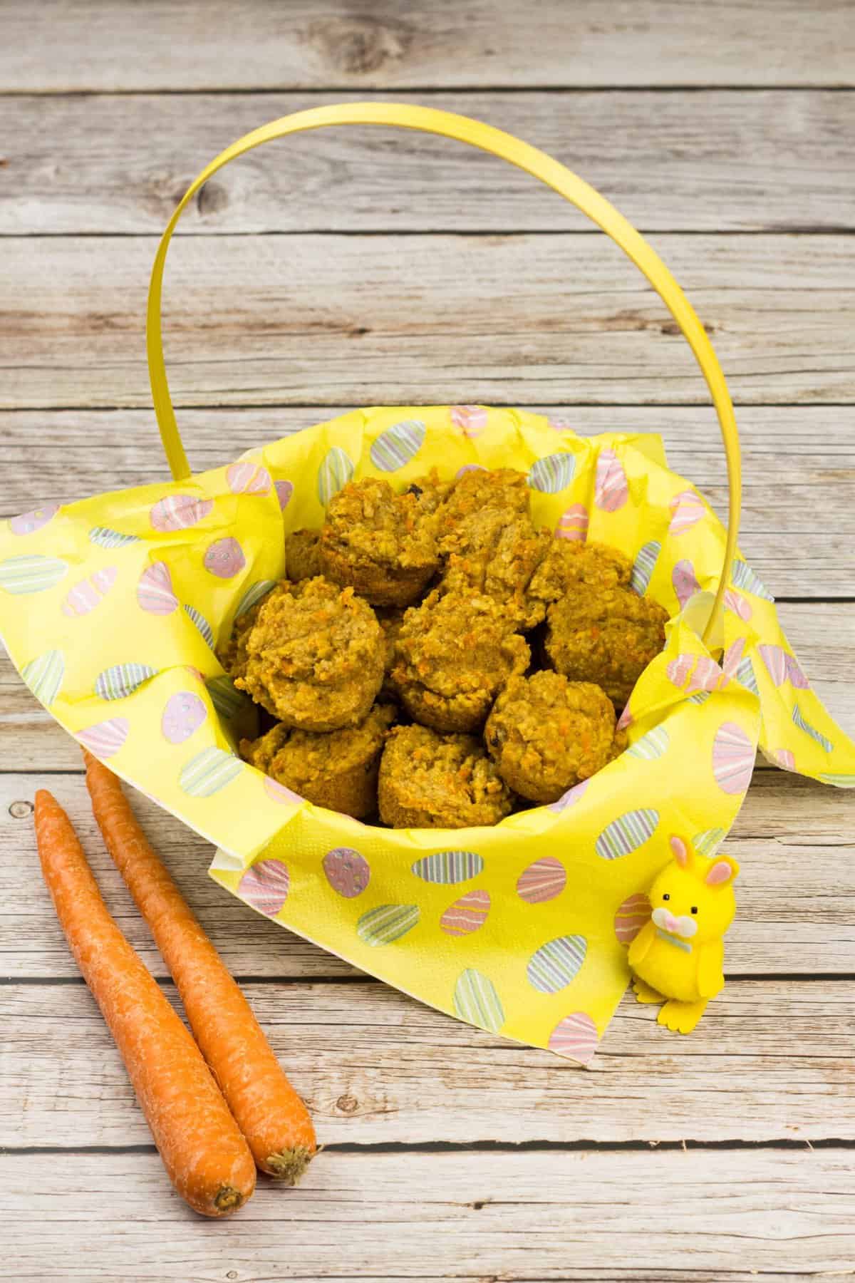 Mini-Karottenmuffins in einem Osterkorb, daneben zwei Möhren