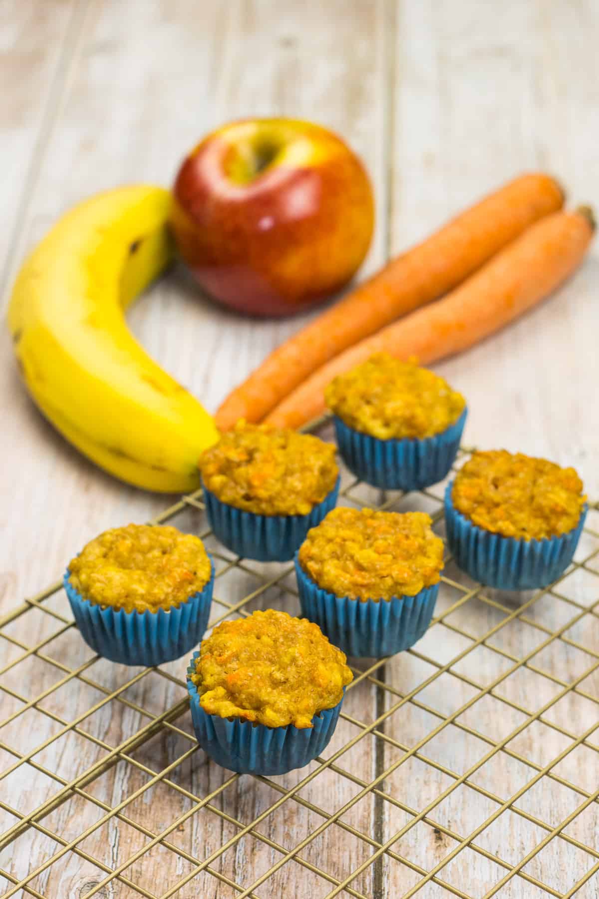 Muffins für Babys ohne Zucker, auf einem Kuchenrost, dahinter liegen eine Banane und Mähren