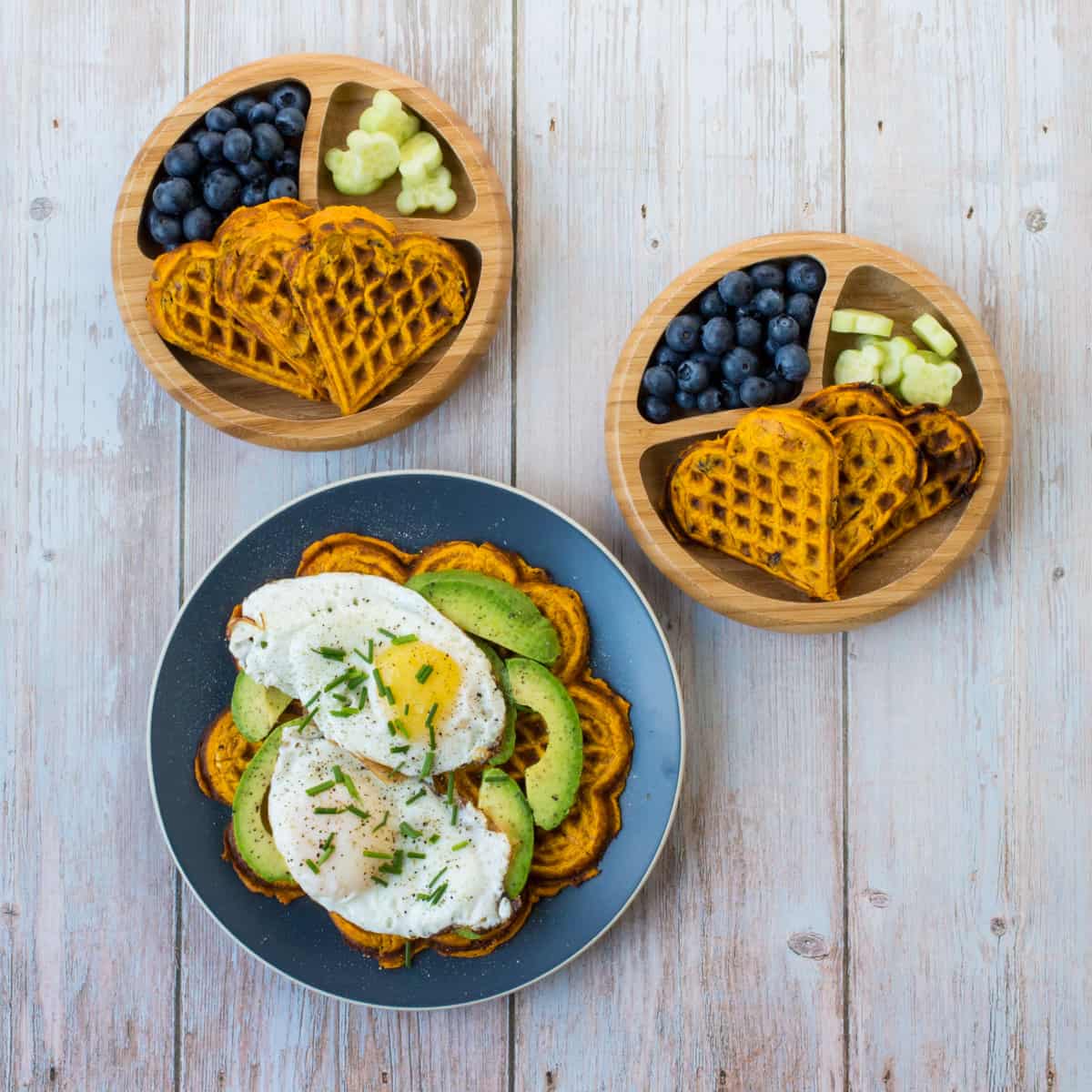 Süßkartoffel Waffel mit Avocado und Spiegelei, daneben zwei Babyteller mit Waffel und Obst