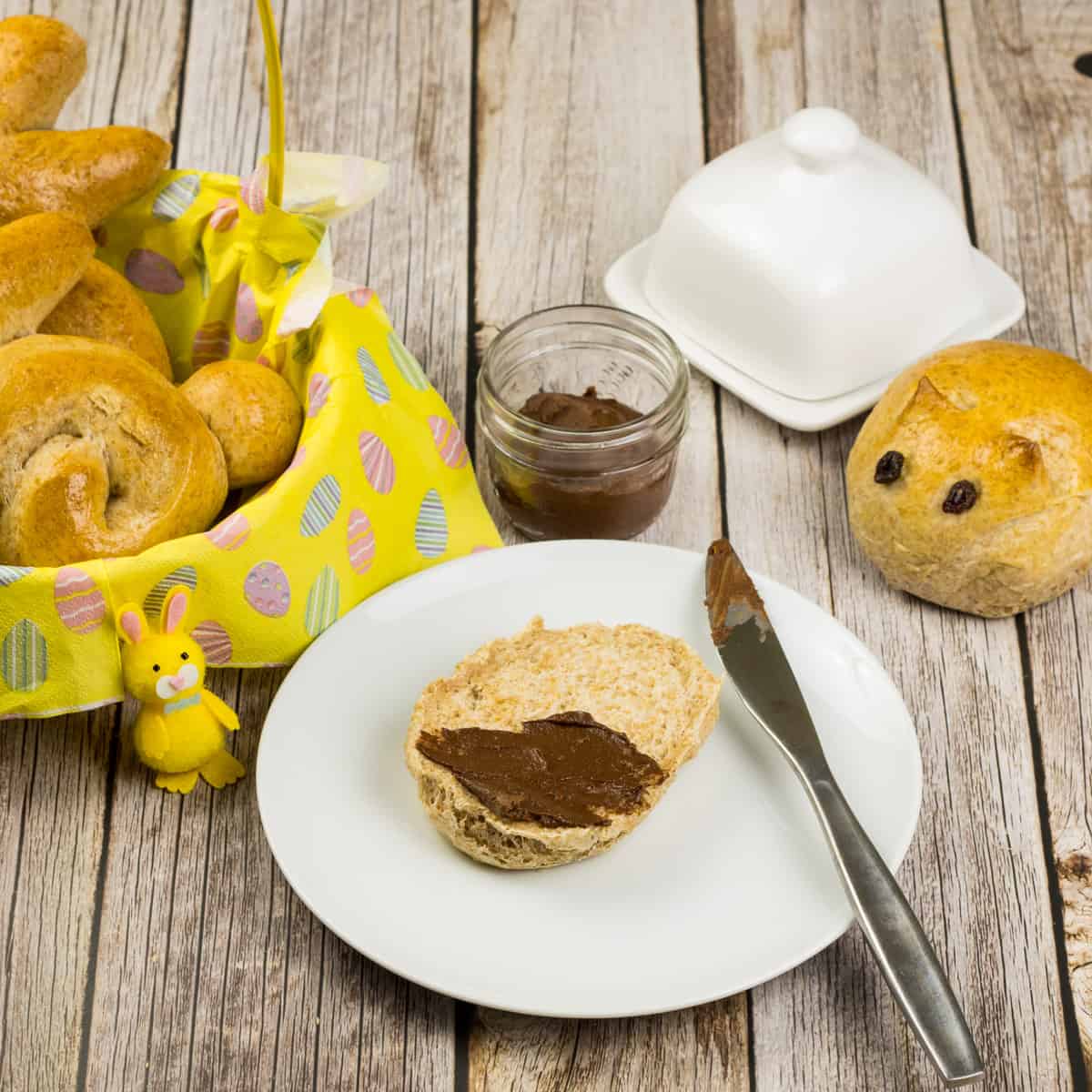 Milchbrötchen, aufgeschnitten auf einem Teller und mit gesunder Schokocreme beschmiert.