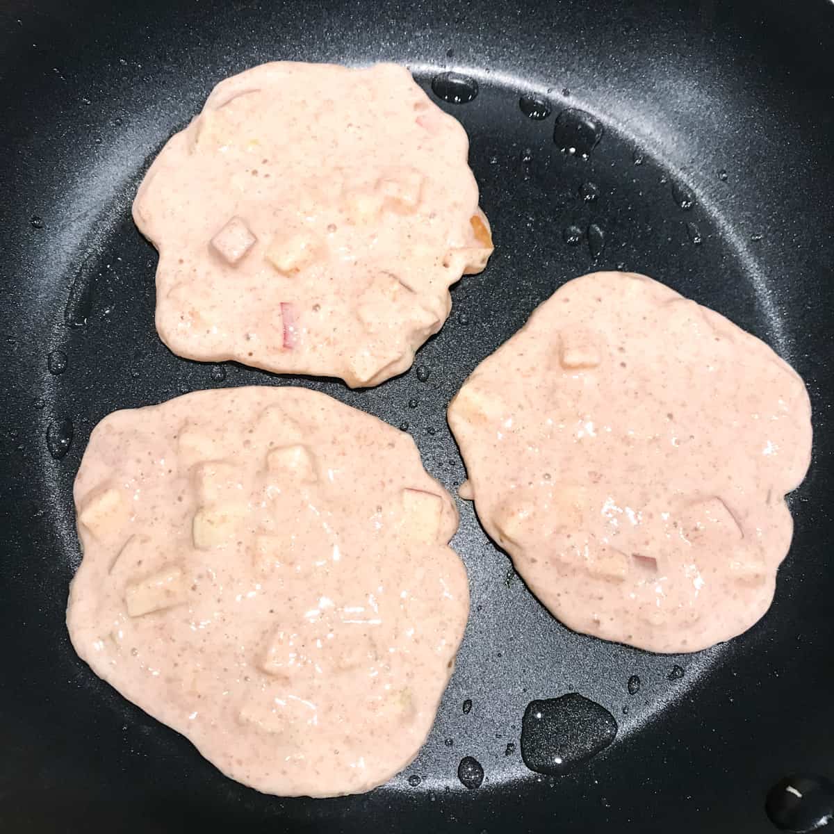 Apfelpfannkuchen die in der Pfanne gebraten werden