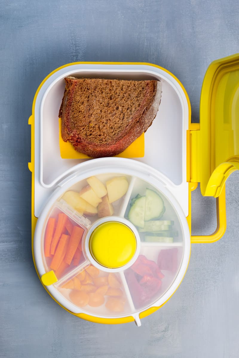 Lunchbox mit Snack Spinner, ein Käsebrot und der Snackspinner ist gefüllt mit Gemuse und Obst