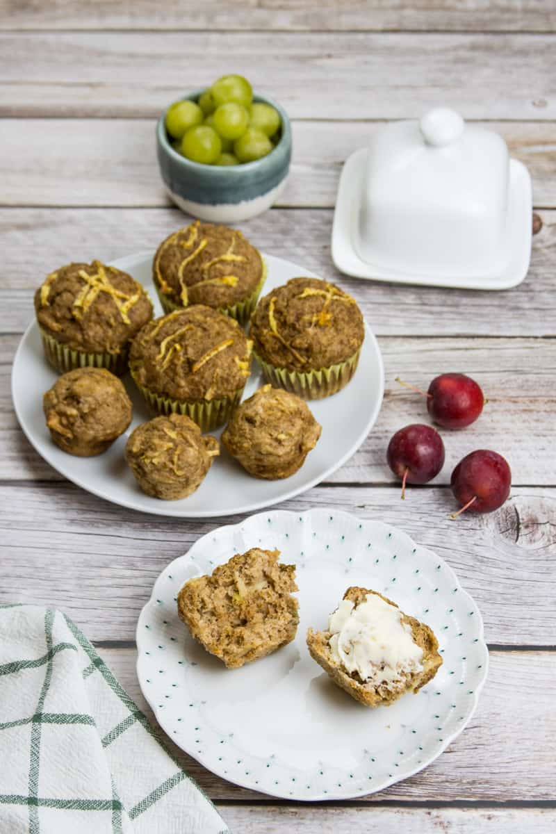 Saftiger Apfelmuffin ohne Zucker, auf einem Teller, in zwei Hälften gebrochen, eine Hälfte ist mit Butter bestrichen