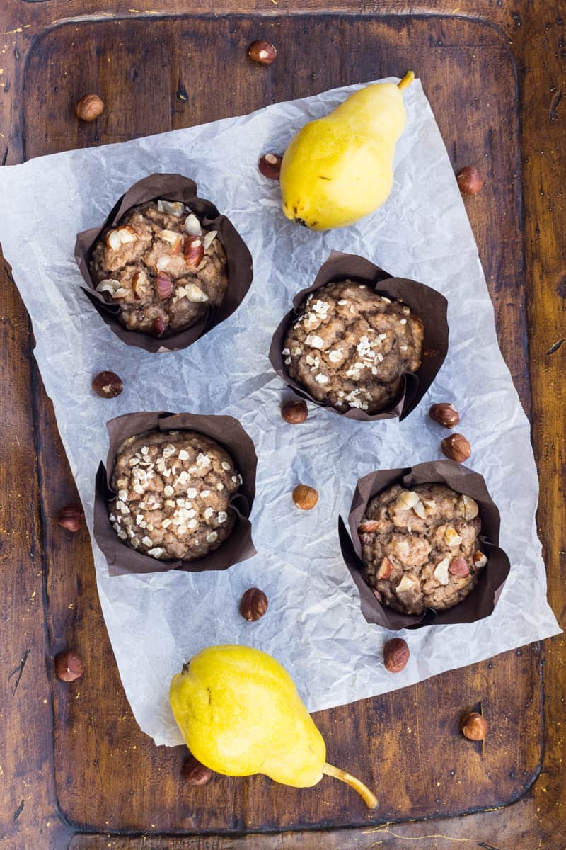 Leckere Birnen-Muffins für die Familie, auf einem Holzbrett, daneben liegen Birnen und Haselnüsse