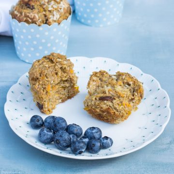 Süße Frühstücksmuffins auf einem Teller, in zwei Hälften gebrochen, mit ein paar Blaubeeren daneben