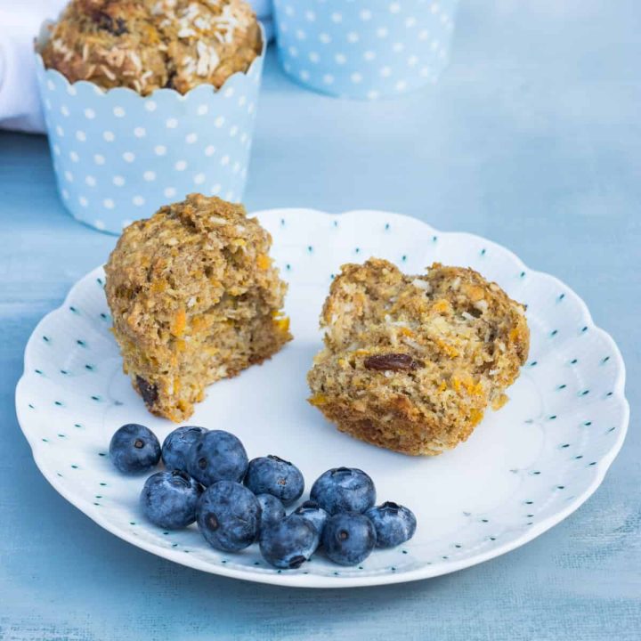 Süße Frühstücksmuffins auf einem Teller, in zwei Hälften gebrochen, mit ein paar Blaubeeren daneben