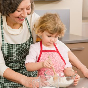 Oma rührt mit Kleinkind einen Teig an, um Plätzchen zu backen