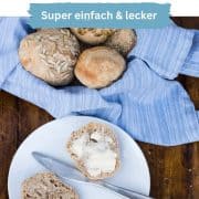 Einfache Dinkelbrötchen über Nacht, in einem Brotkorb, ein fluffiges Brötchen ist aufgeschnitten auf einem Teller, mit Butter beschmiert