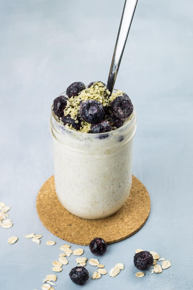 Overnight Oats mit Joghurt, sowie Blaubeeren und Hanfsamen als Topping, in einem Glas