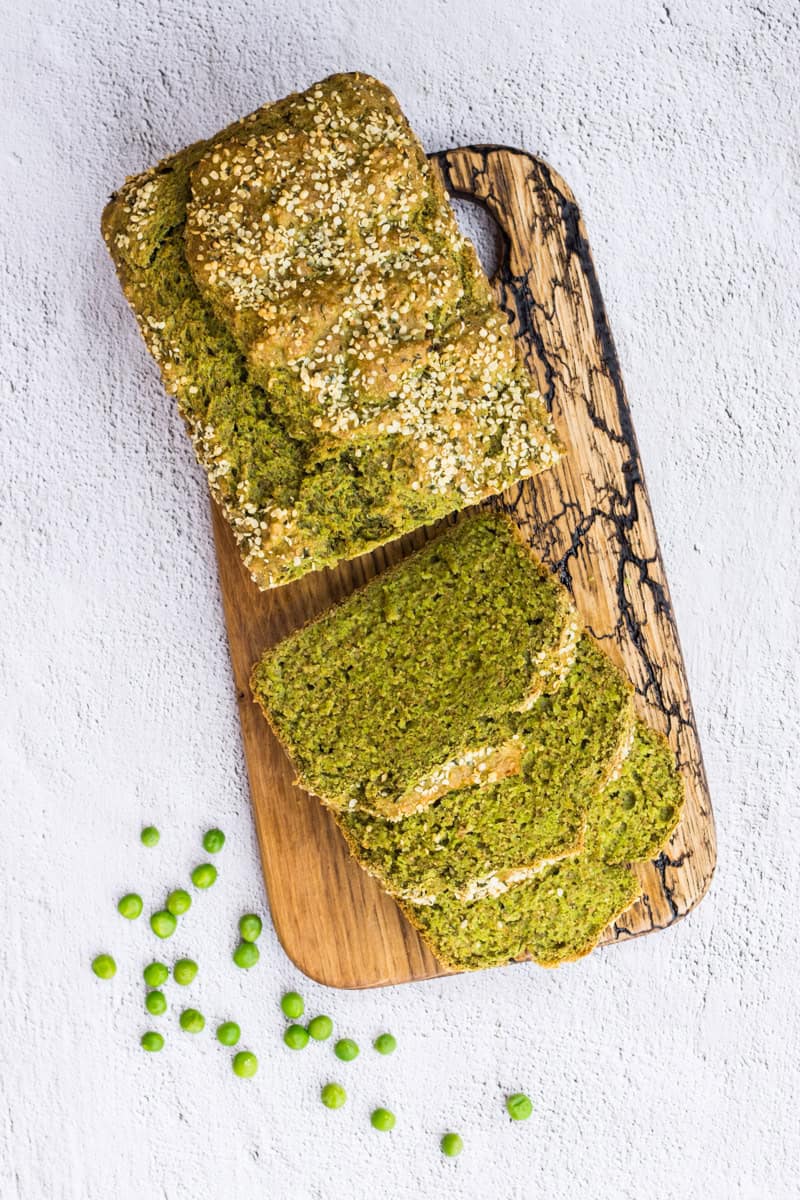 Grünes Erbsenbrot mit viel Gemüse, aufgeschnitten auf einem Holzbrett