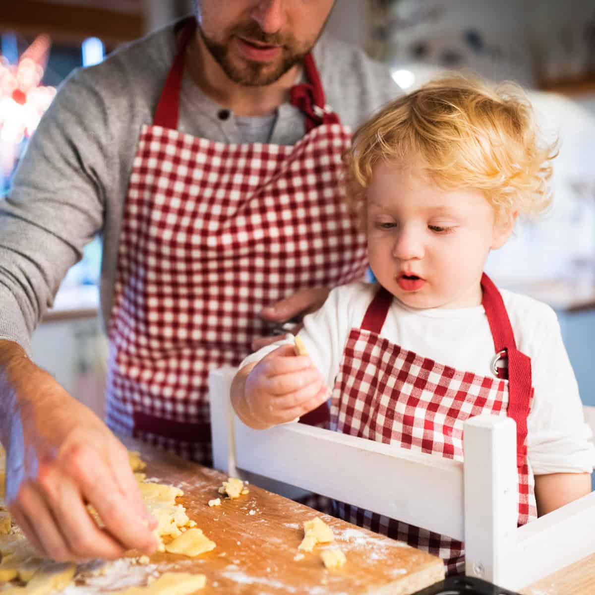 Vater und Sohn backen gemeinsam Kekse, dabei steht das Kind auf einem Learning Tower